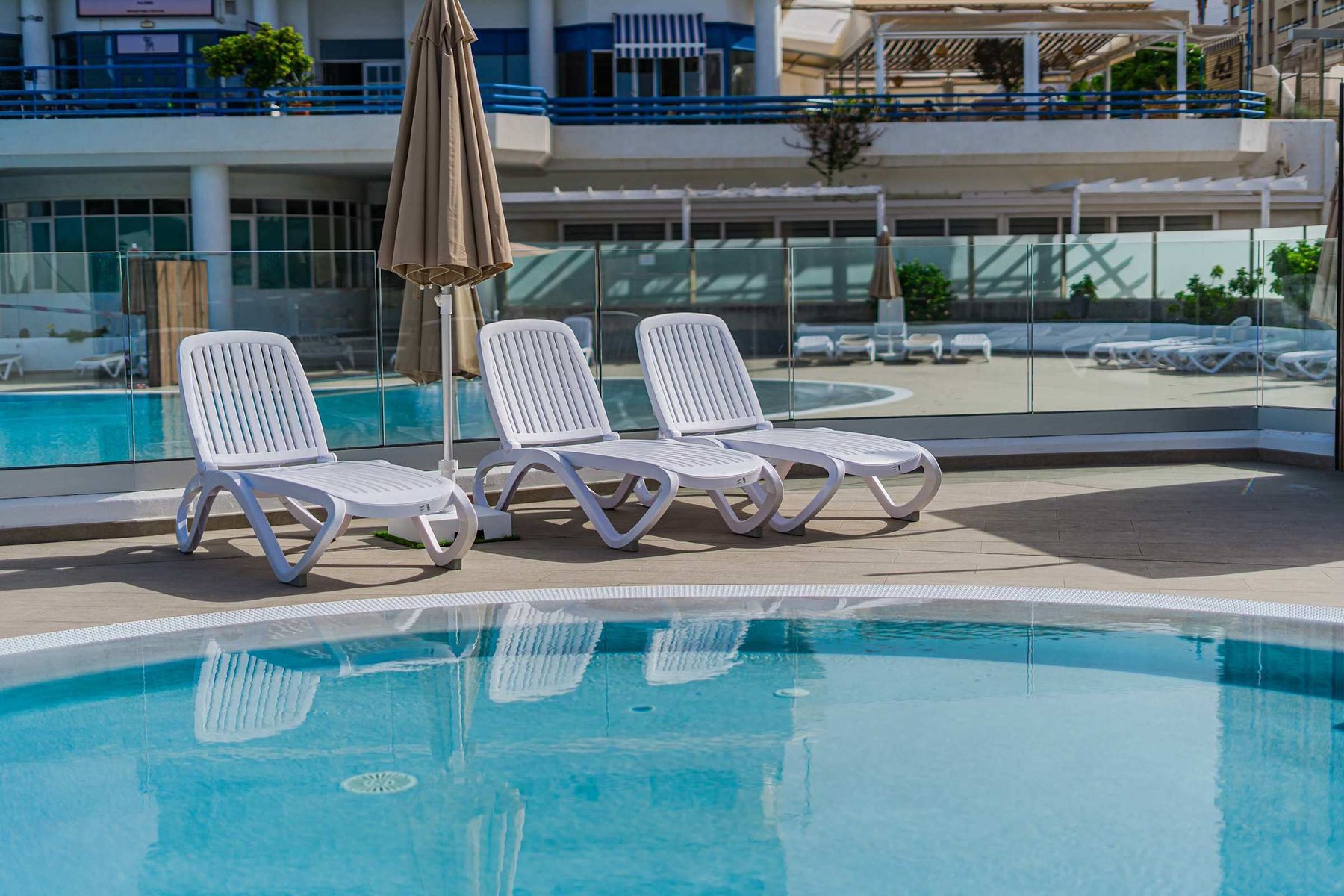 Resort-Style Pool Area with Sun Loungers and Open-Air Relaxation Space