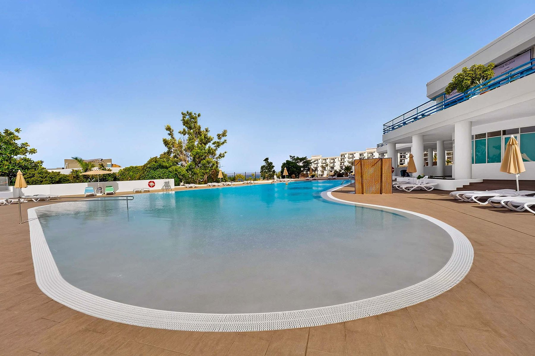 Resort-Style Pool Area with Sun Loungers and Open-Air Relaxation Space