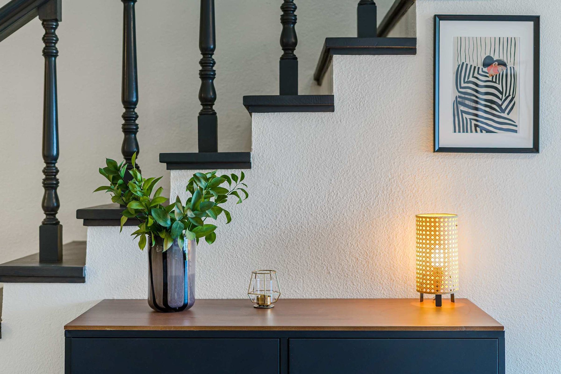 Boutique-Style Welcome by the Stairs — Soft Lighting, Fresh Greenery & Framed Art Create a Peaceful Entrance Vibe
