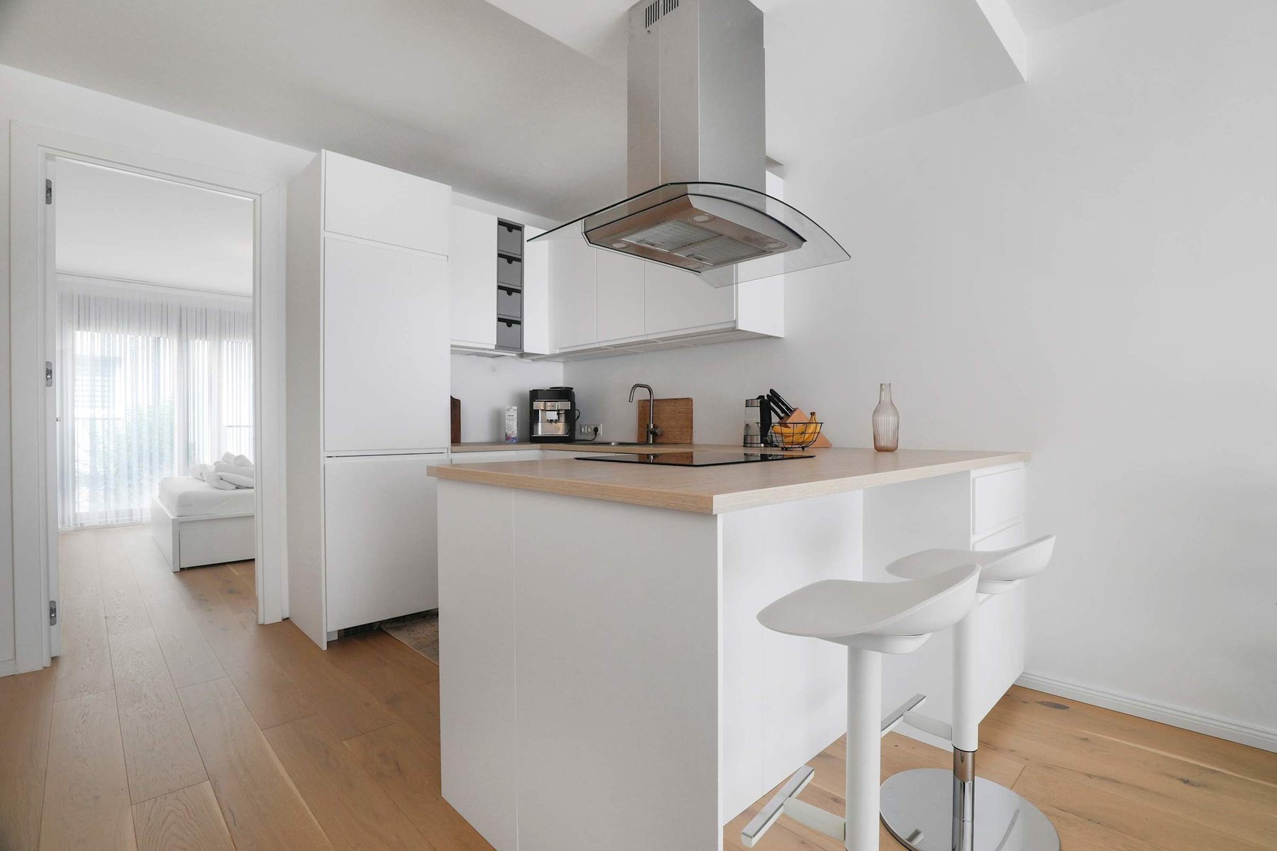 Sleek White Kitchen with Integrated Storage and Bedroom Access