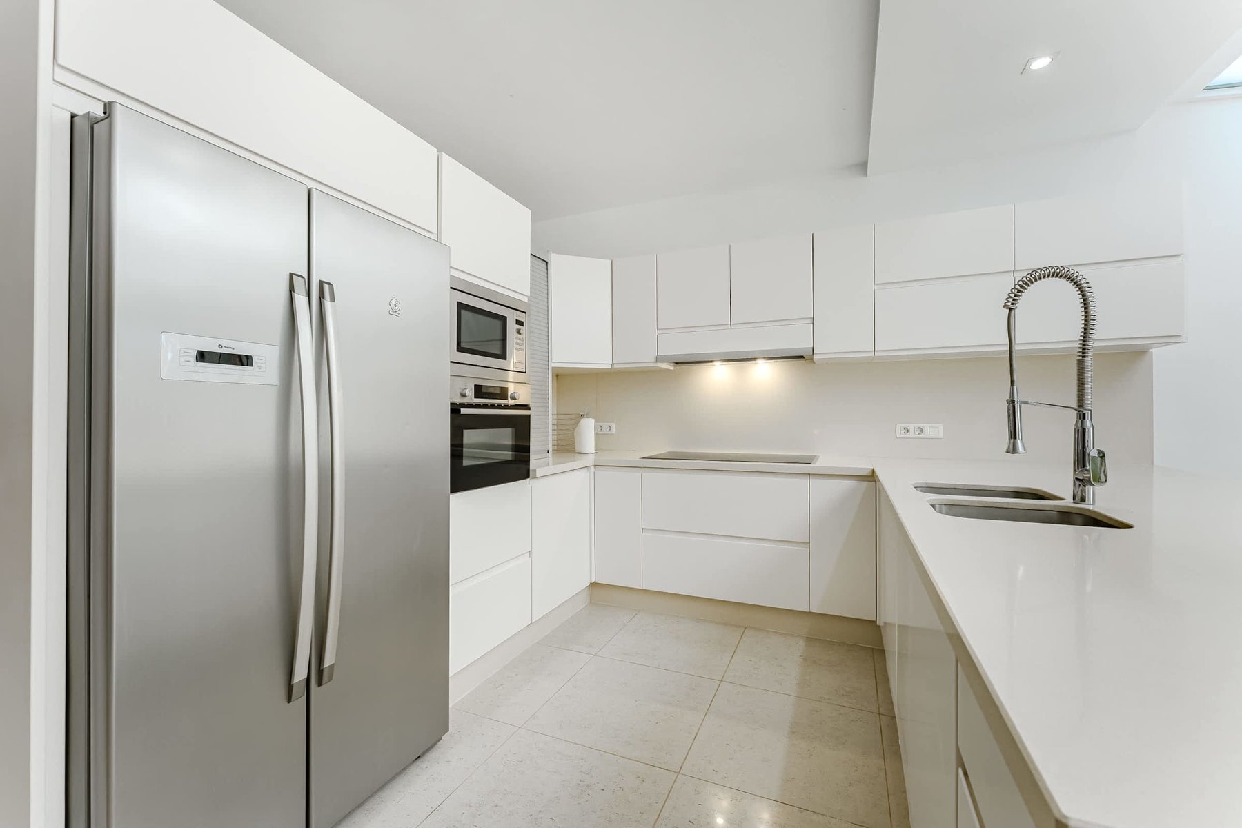 Sleek Modern Kitchen with Full-Size Stainless Steel Appliances, Generous Countertops, and Minimalist White Cabinetry