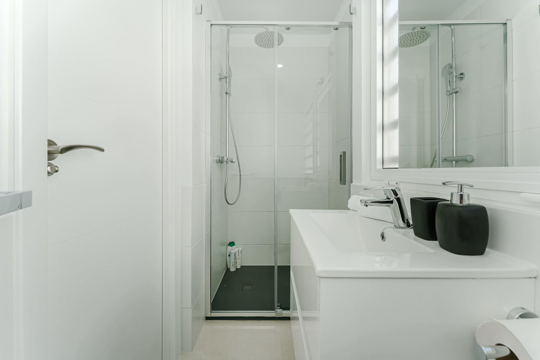 Minimalist Third Bathroom with Glass Shower, Backlit Mirror, and Matte Black Accessories for a Modern Spa Feel