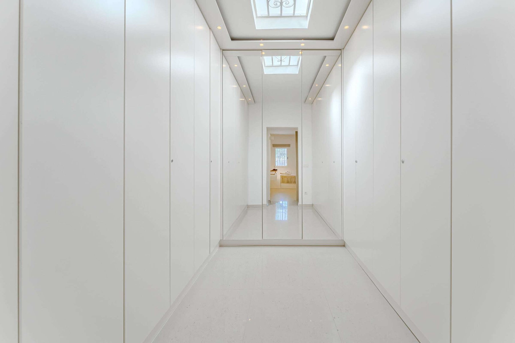 Minimalist Walk-In Closet with Full-Length Mirrors and Skylight – A Bright and Spacious Dressing Retreat