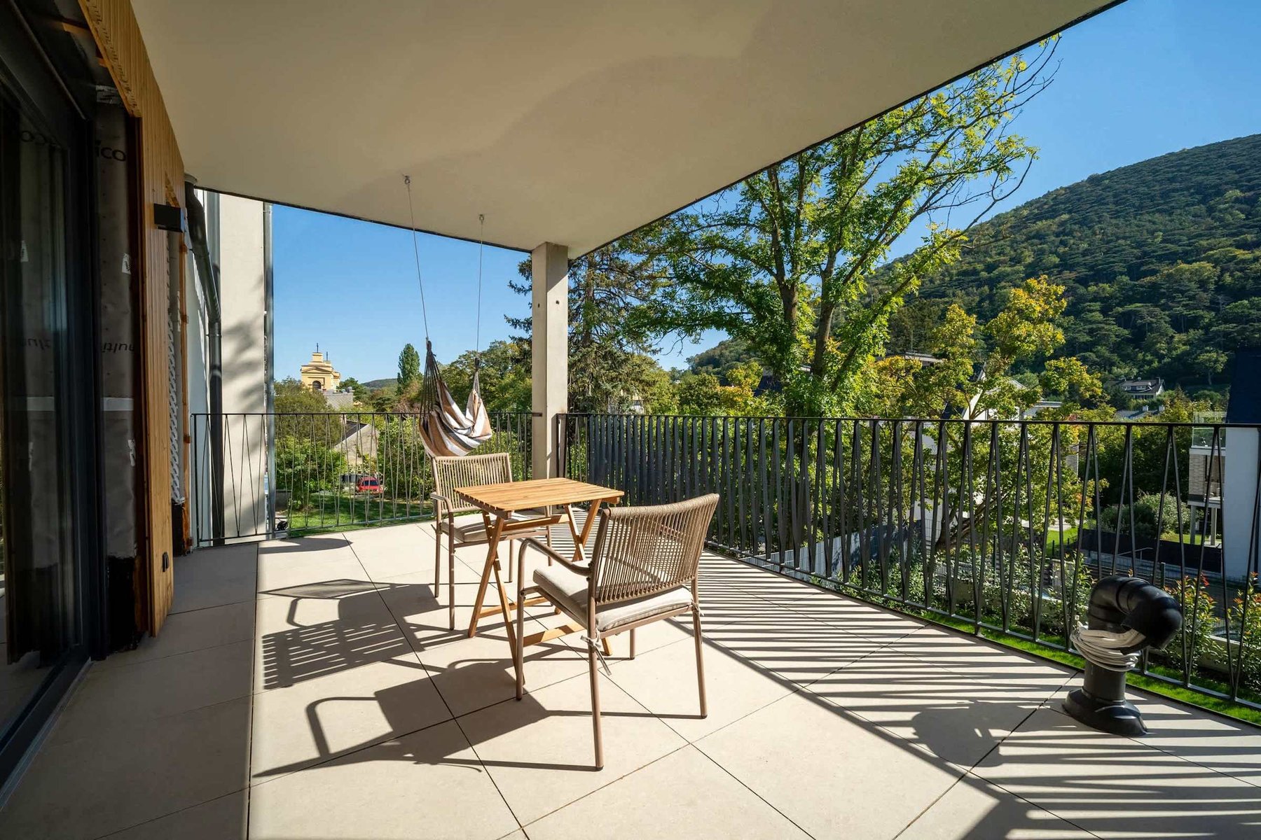 Covered balcony with outdoor dining and views of the wooded hills