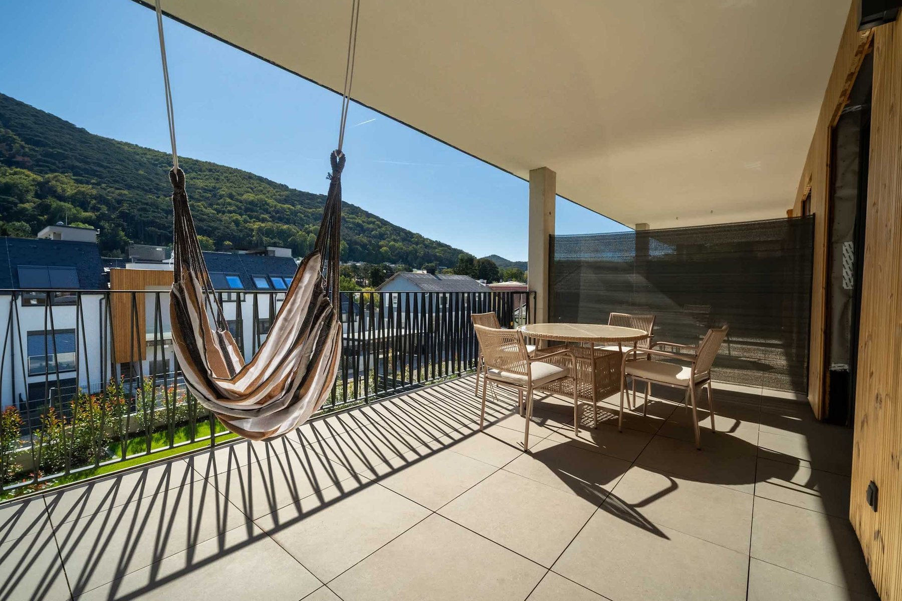 Covered balcony with hanging chair, dining table and views of the wooded hills